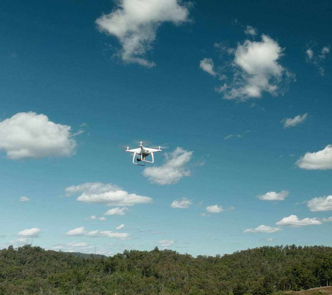 A white GroundProbe drone using BlastVision flying in the sky above a mine site