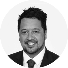 A black and white photo of a man with short dark hair posing for a headshot photo.