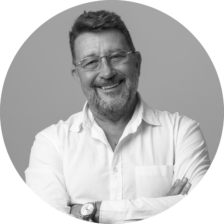 A black and white photo of a man posing for a company headshot.
