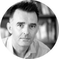 A black and white photo of a man with short dark hair posing for a headshot photo.